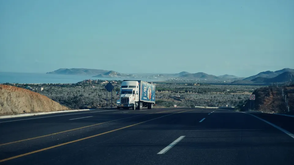A semi truck on a divided highway with hills in the distance