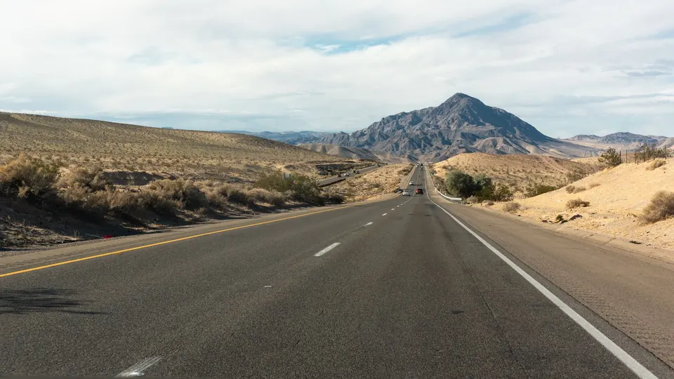 An open two-lane highway through desert hills