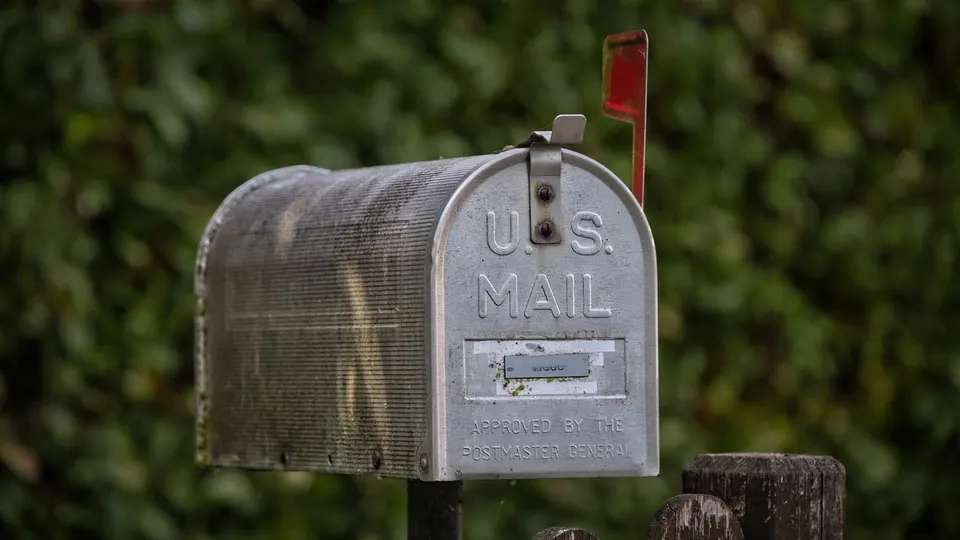 A gray U.S. Mail box on a post