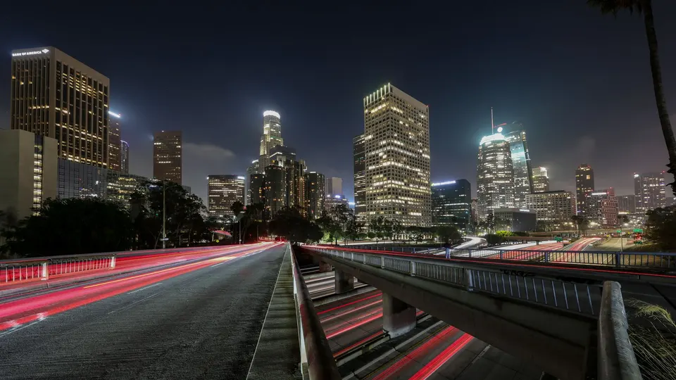 Downtown Los Angeles towers at night above a freeway with light trails