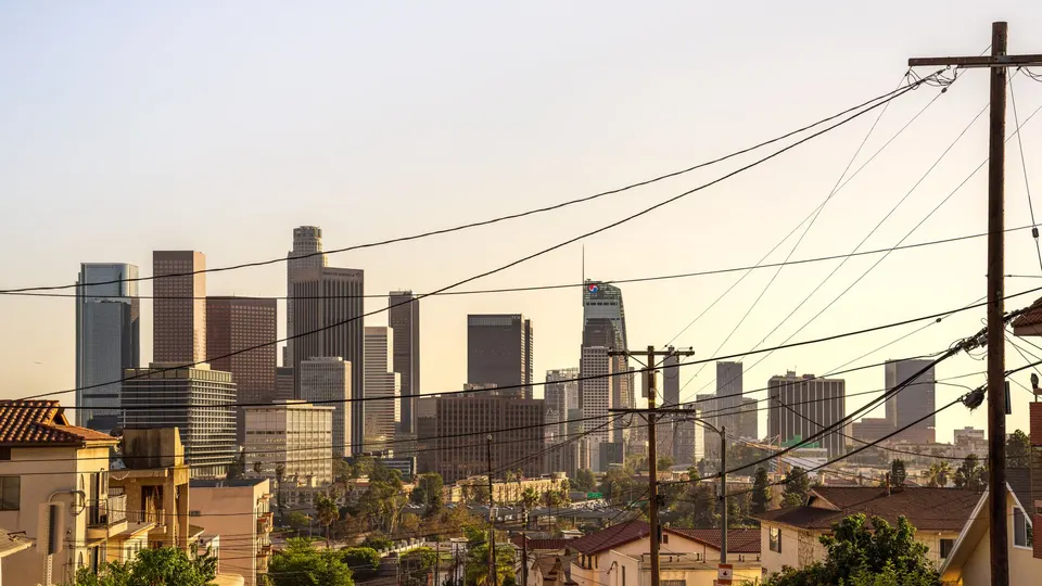 The downtown Los Angeles skyline seen over rooftops and utility wires