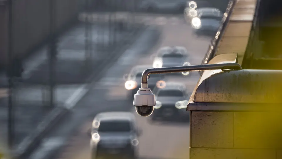 A dome camera mounted over a busy road with cars below