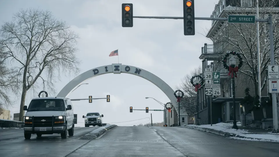 Traffic signals over a small-town intersection with an American flag