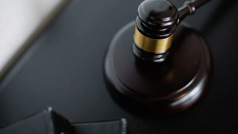 A wooden gavel and sound block on a dark courtroom table