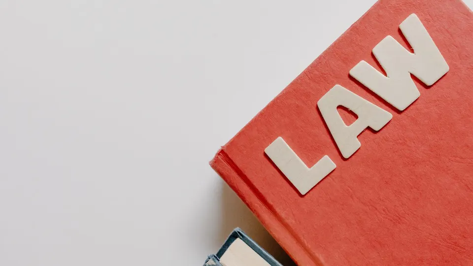 A red law book resting on another book against a plain background