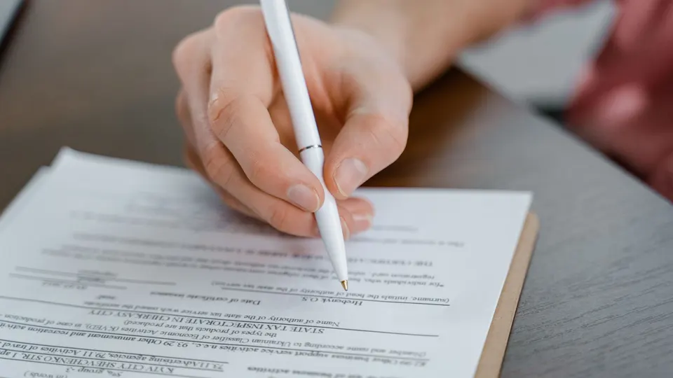 A hand writing on a form with a white pen